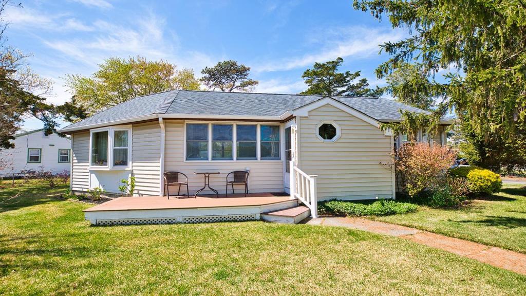 a small white house with a porch on a yard at Cape Bay Cottage in North Cape May