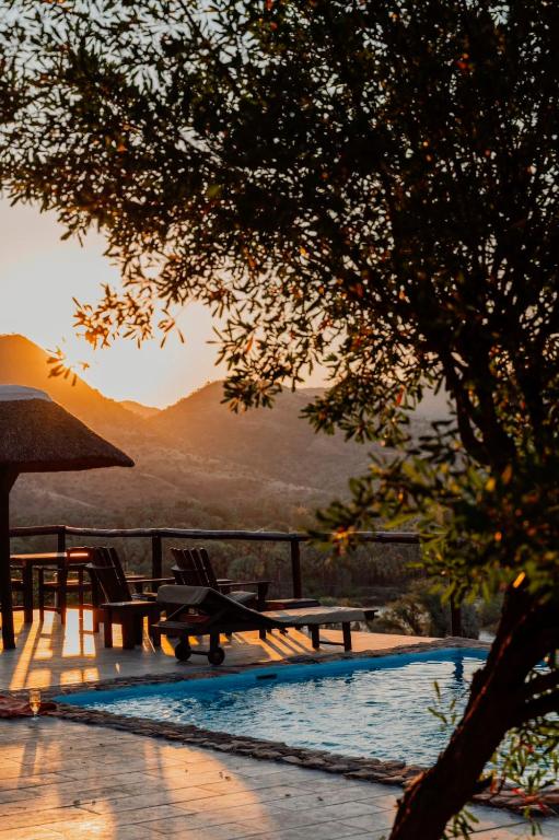 a pool with chairs and a table and a tree at Kapika Waterfall Lodge in Epupa