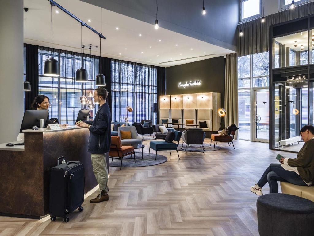 a man standing at a counter in a lobby at ibis Styles Bielefeld City in Bielefeld