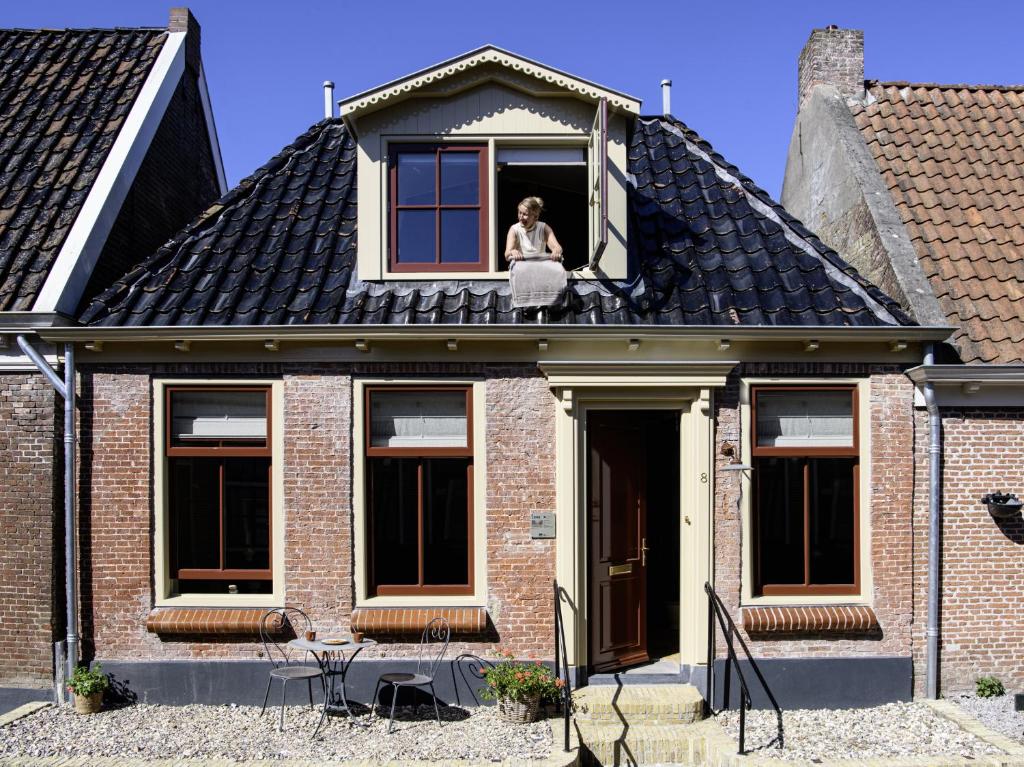 a woman is looking out the window of a house at Walingsuites in Holwerd
