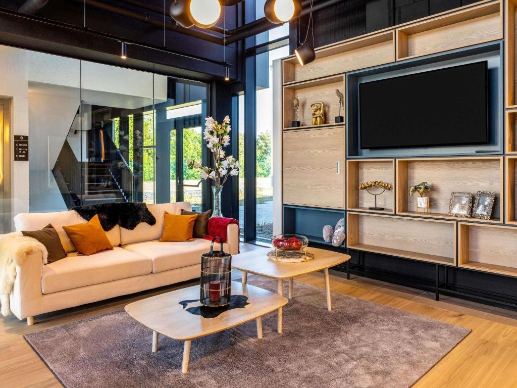 a living room with a couch and a tv at ibis Brussels Groot Bijgaarden in Groot-Bijgaarden