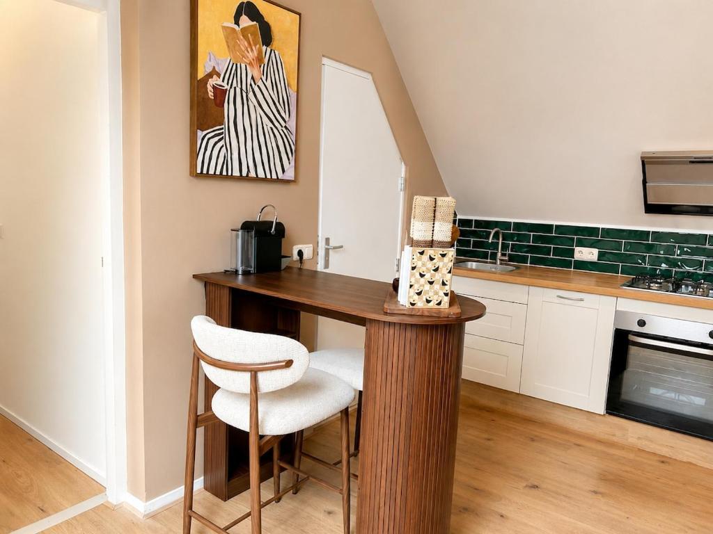 a kitchen with a wooden table and a chair at Wonenmeteenknipoog Groningerweg 23D in Peize