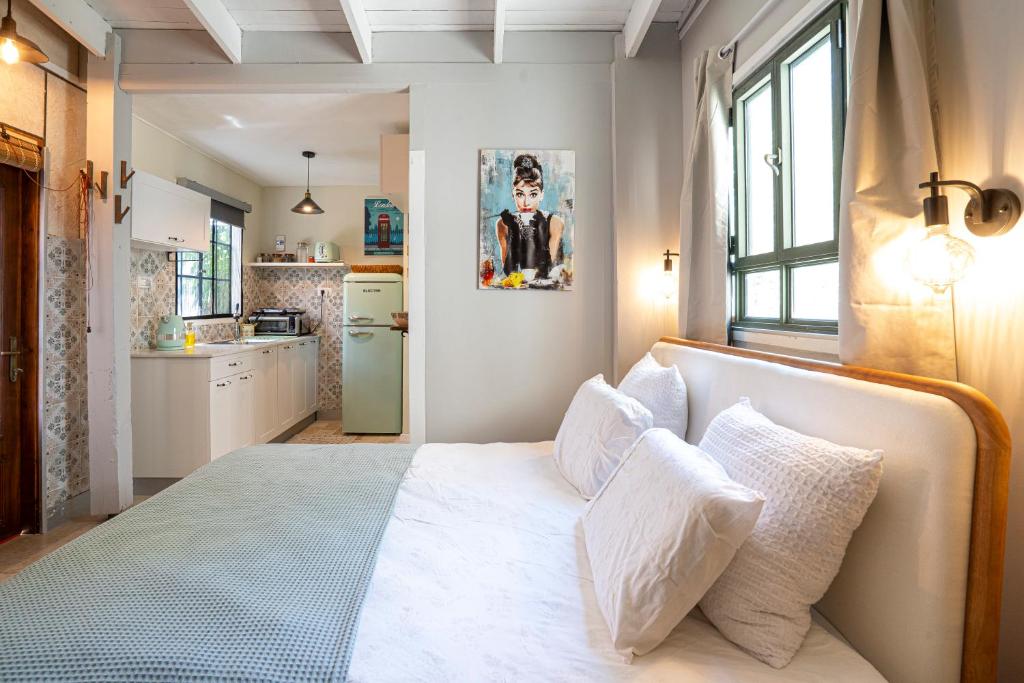 a bedroom with a large white bed with pillows at בצל הדקל in Bet Leẖem HaGelilit
