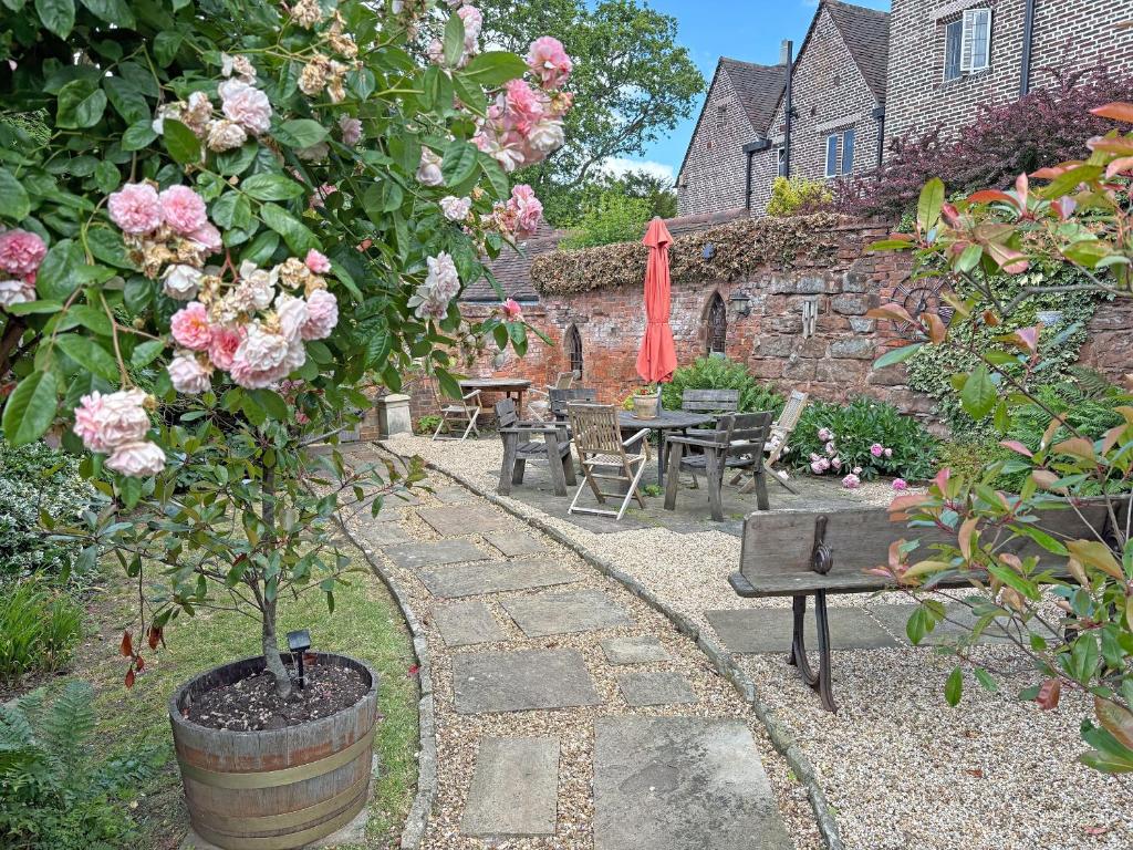 a garden with a table and a bench and roses at Ye Olde Stone House in Sutton Coldfield