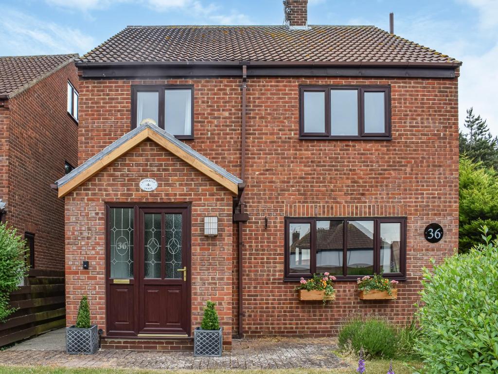 a red brick house with a brown door and windows at Evergreen House in Runswick