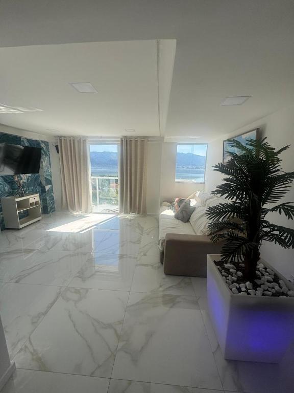 a living room with a couch and a palm tree at Mirante Piratininga - Casa 2 quartos - Vista Panorâmica Lagoa e Praia in Niterói