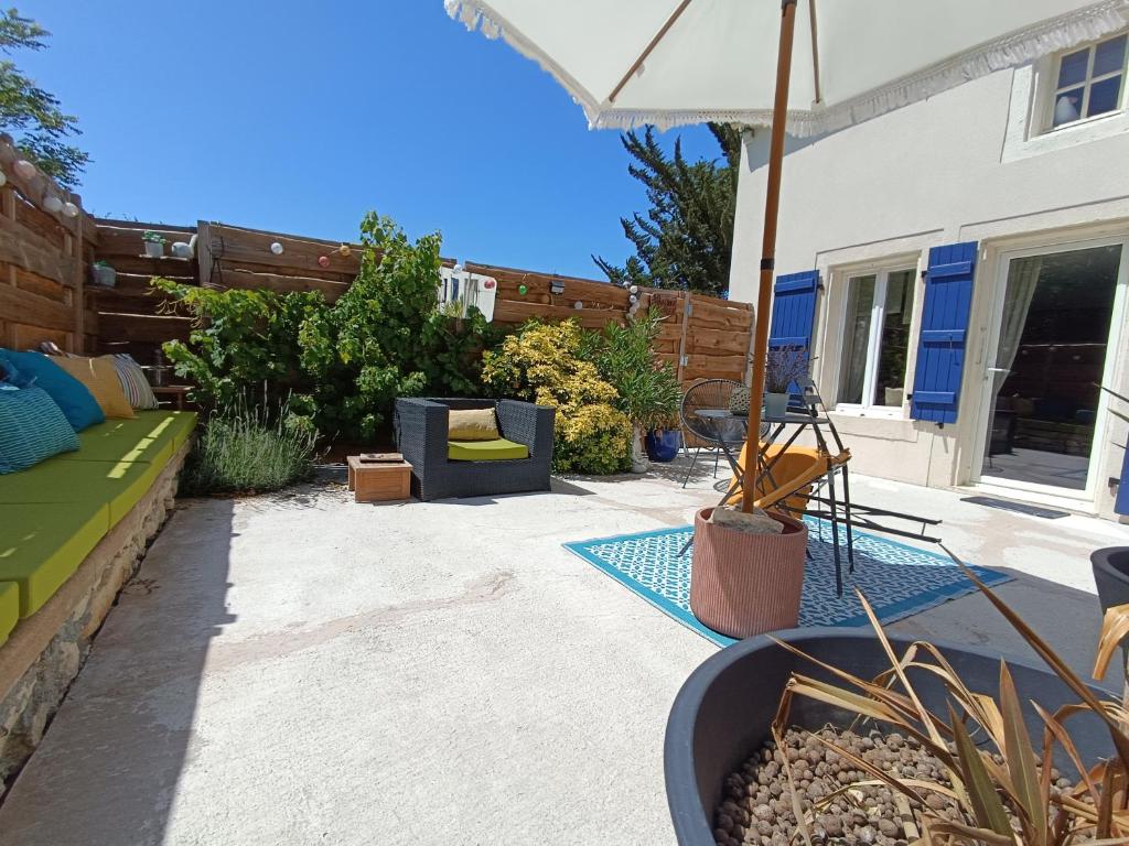 a patio with an umbrella and some plants and a patio at La chambre d'Hôt'ize in Bouillé-Courdault