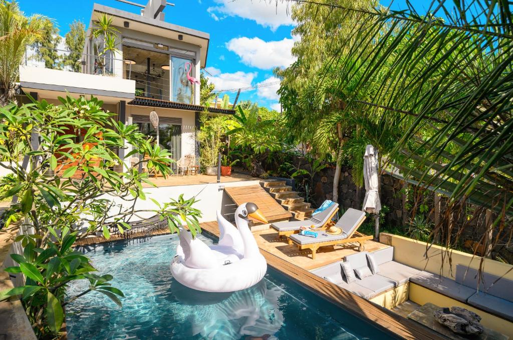 a swimming pool with two swans in a backyard at Villa Mauritius - Designer Private Studios in Pointe aux Sable