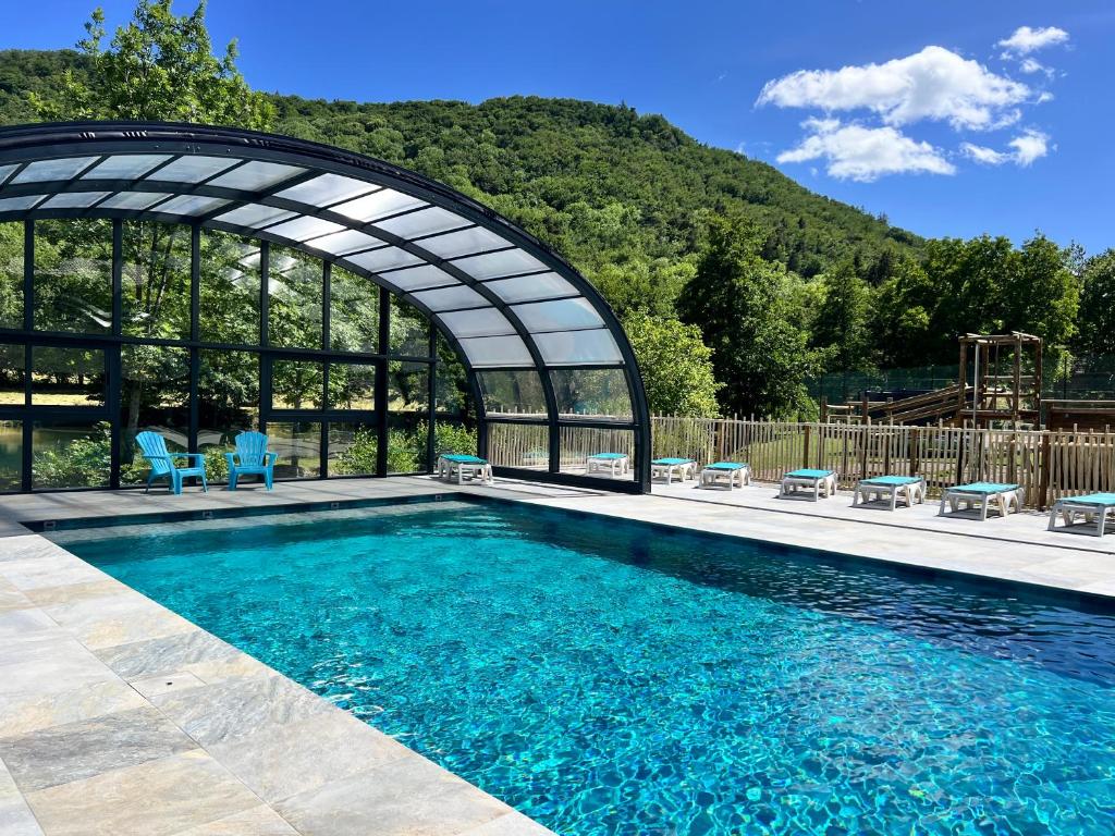 a swimming pool with blue chairs and a building at Résidence Les Dômes in Murol