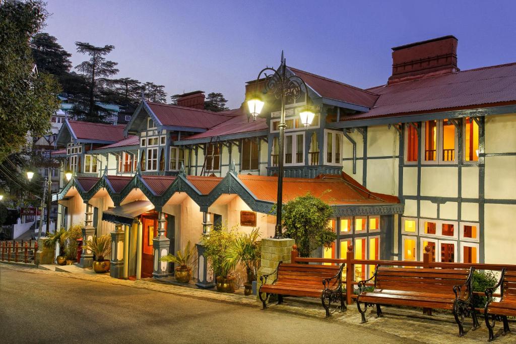 
a row of wooden benches in front of a building at Clarkes hotel, A grand heritage hotel since 1898 in Shimla
