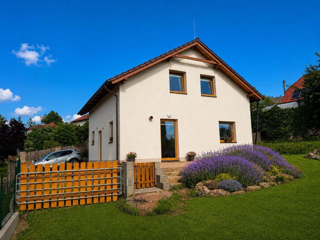 a white house with a fence and purple flowers at Apartmán U nás na vsi in Nový Jáchymov