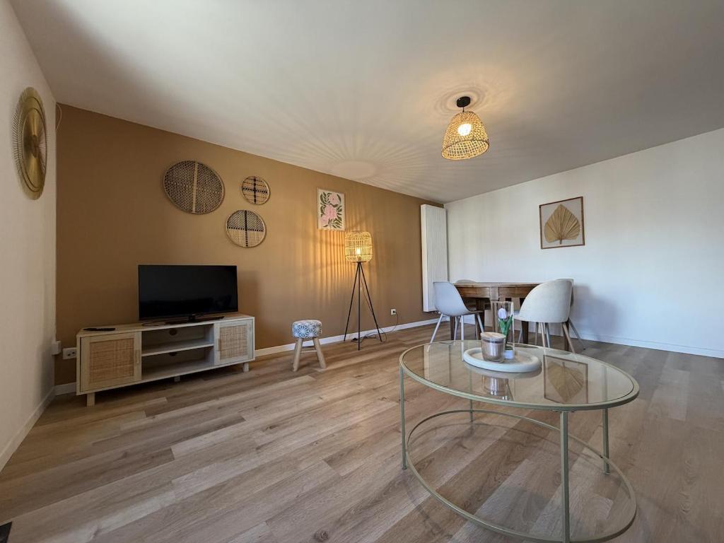 a living room with a glass table and a television at Mon petit cocon Seurrois in Seurre