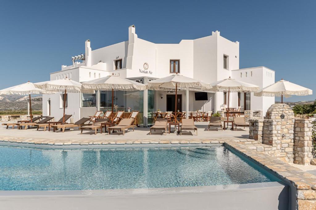 a villa with a swimming pool with chairs and umbrellas at Naxian Air in Naxos Chora