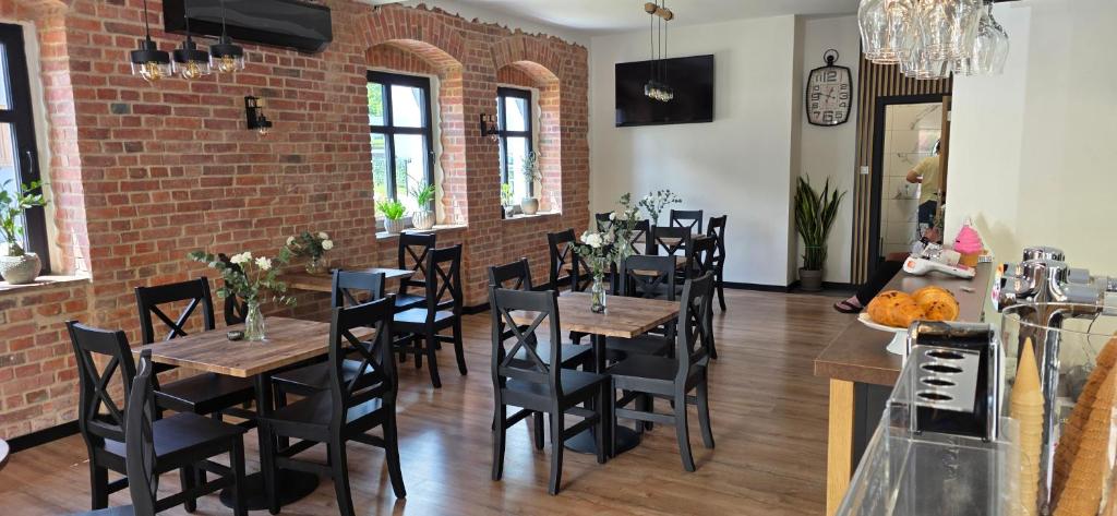 a restaurant with wooden tables and chairs and a brick wall at Turystyczna 9 apartamenty & cafe in Sobótka