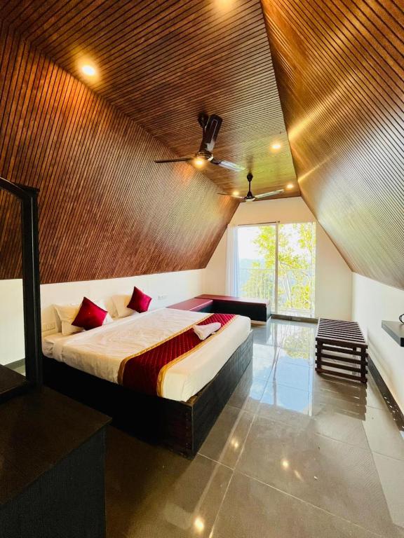 a bedroom with a large bed with a wooden ceiling at Oxygen Rain Forest Resort in Kūmudi