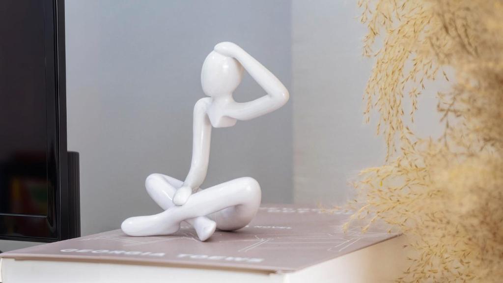 two white sculptures sitting on a table next to a vase at Cozy house at Central Hatyai in Sathani Khlong Rian