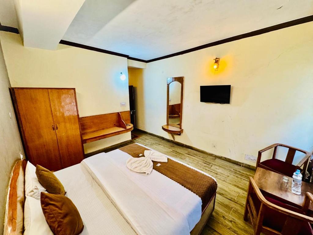 a bedroom with a bed and a table and a television at Hotel Rana Taradevi in Shimla