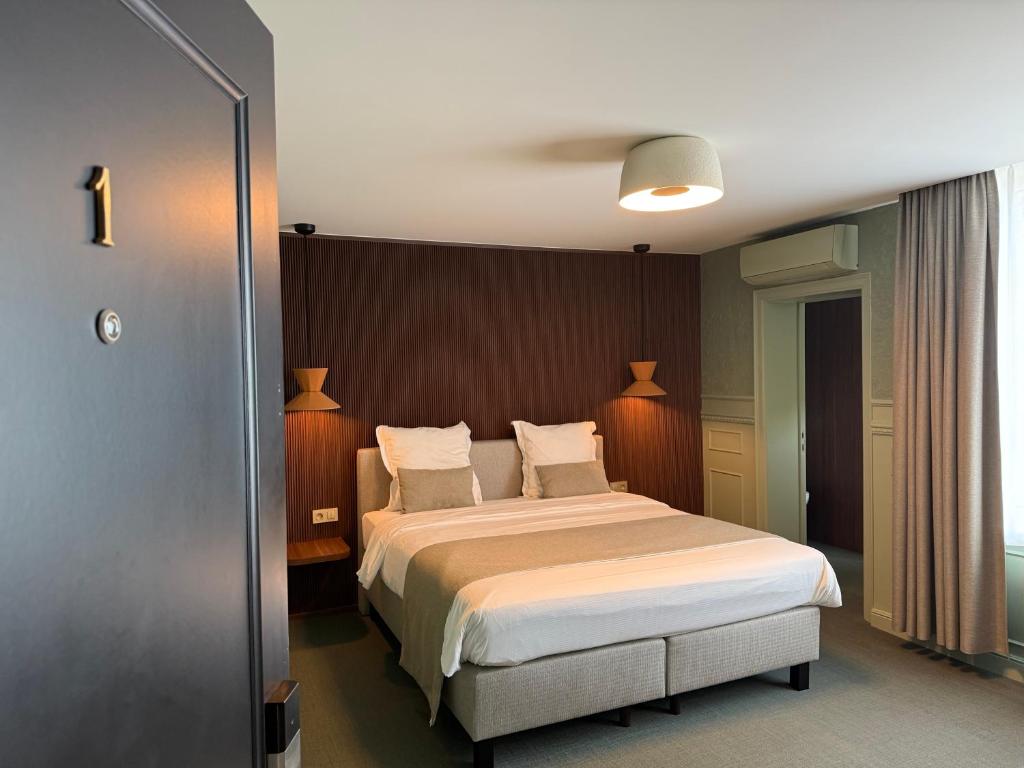 a bedroom with a large bed with white sheets and pillows at Hotel Amfora in Poperinge