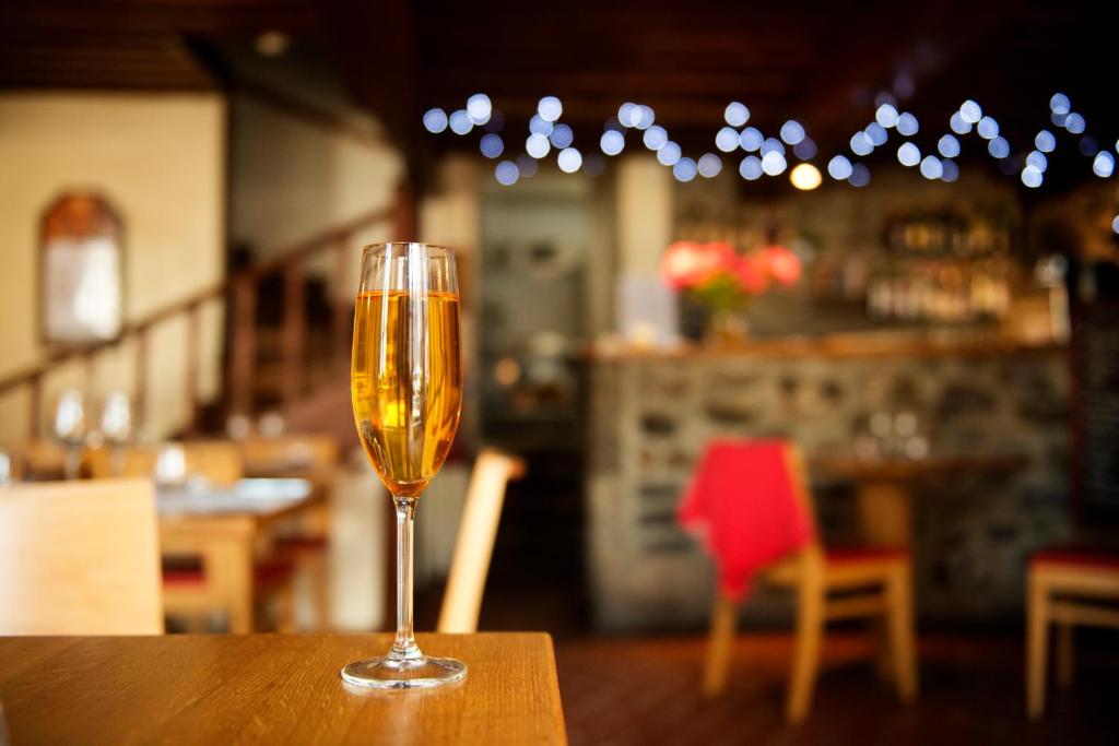 a glass of champagne sitting on a table in a restaurant at Auberge Le Cantou - Hôtel Roche in Orcival