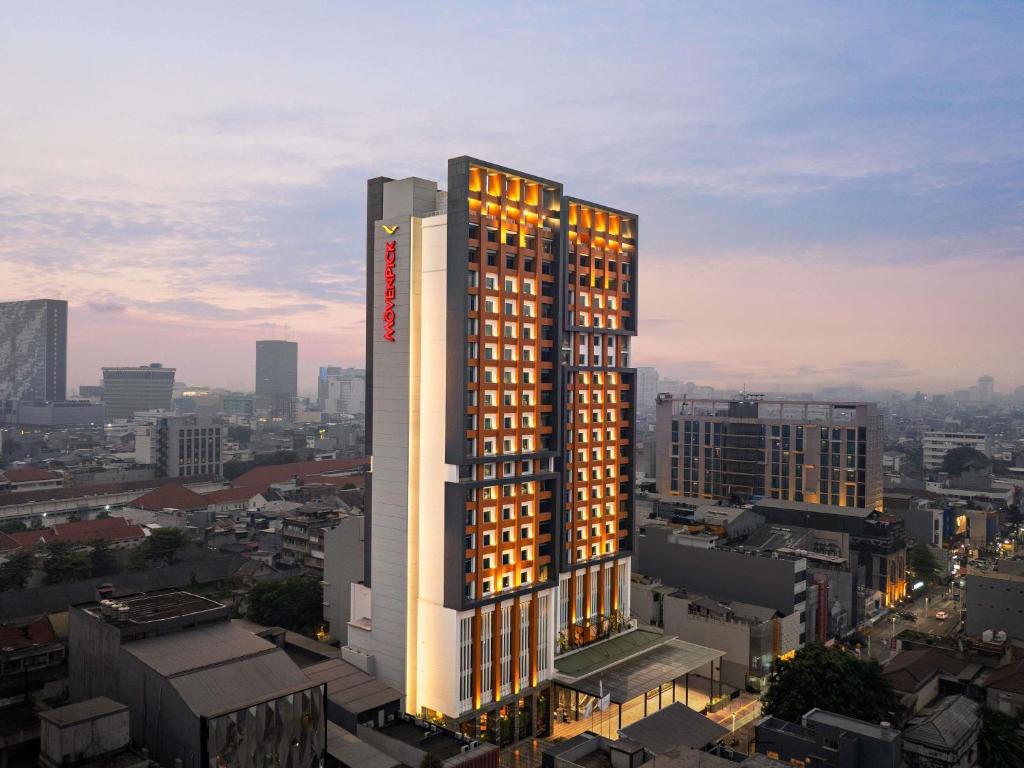 a tall building with lights on in a city at Mövenpick Hotel Jakarta City Centre in Jakarta