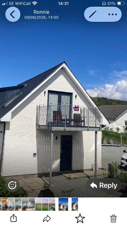 a white house with a balcony on top of it at Skyefall Apartment in Uig
