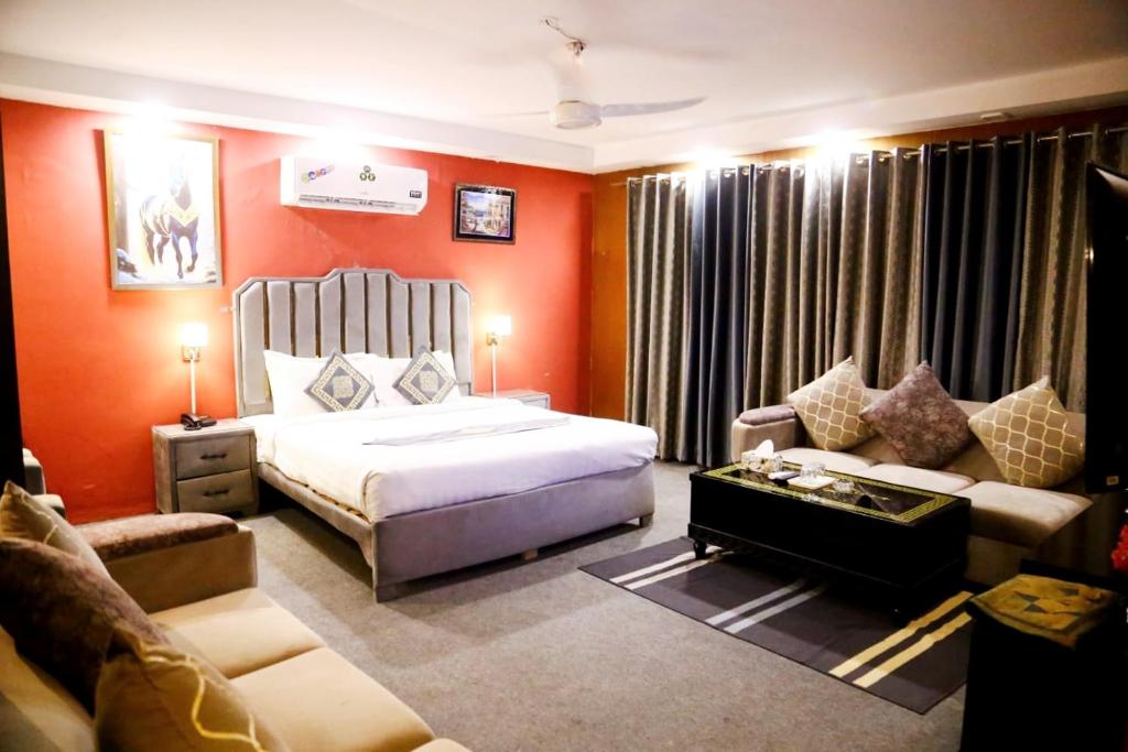 a bedroom with orange walls and a bed and a couch at Palm East Hotel in Lahore