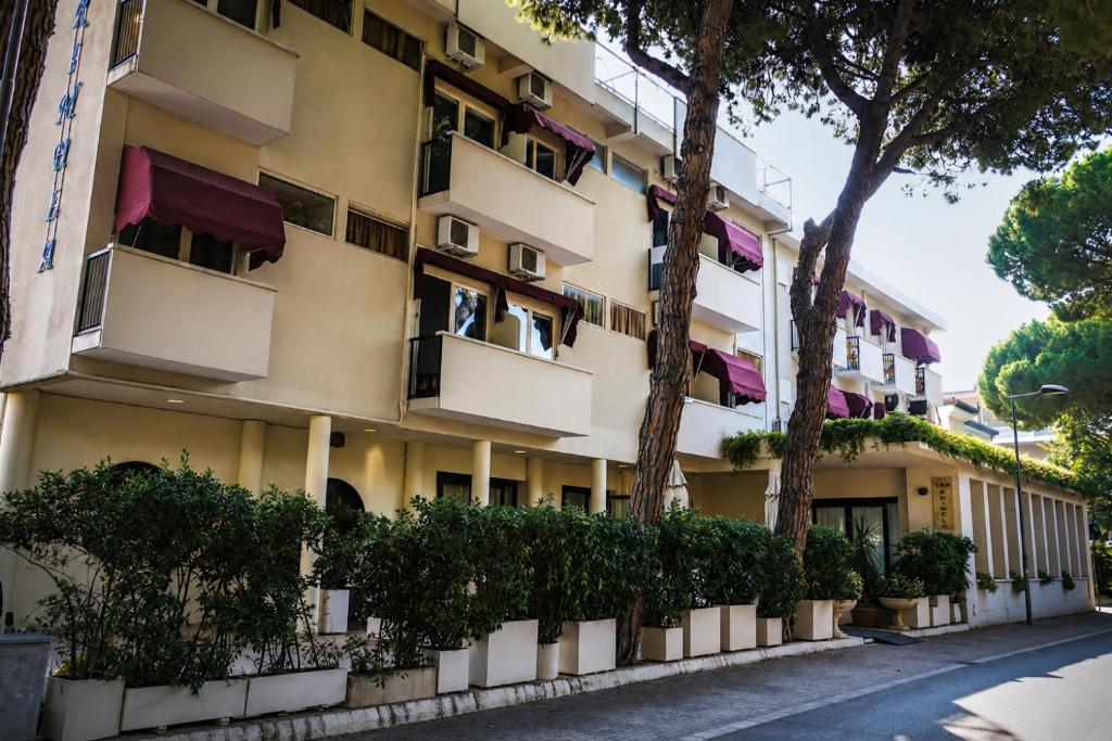 an apartment building with trees in front of it at Hotel New Primula in Rimini