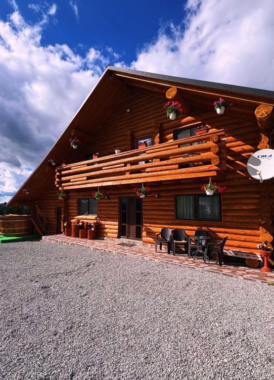 a log cabin with tables and chairs in front of it at Cabana Colț De Munte in Ocoale