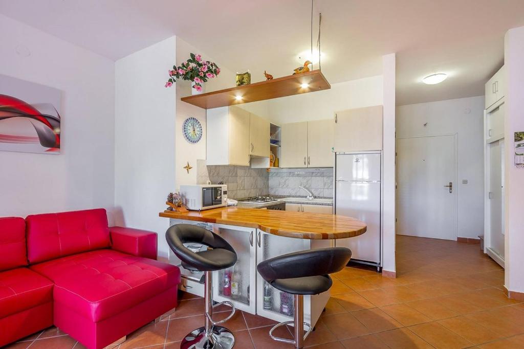 a living room with a red couch and a kitchen at Apartments Villa Ana in Medulin