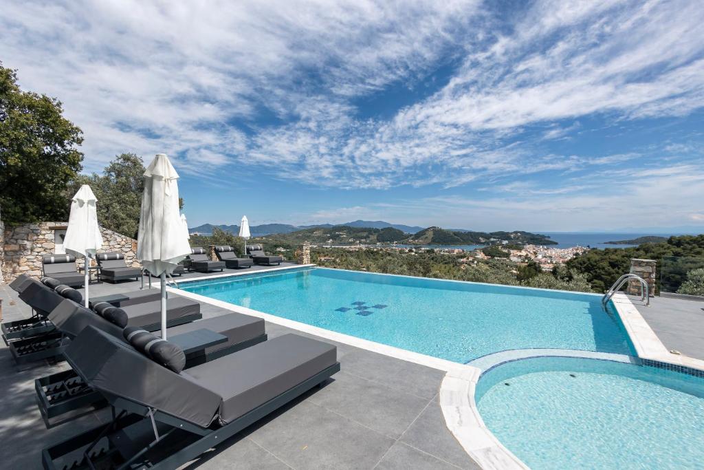 a swimming pool with chaise lounge chairs next to a swimming poolvisor at Skiathos Garden Cottages in Skiathos