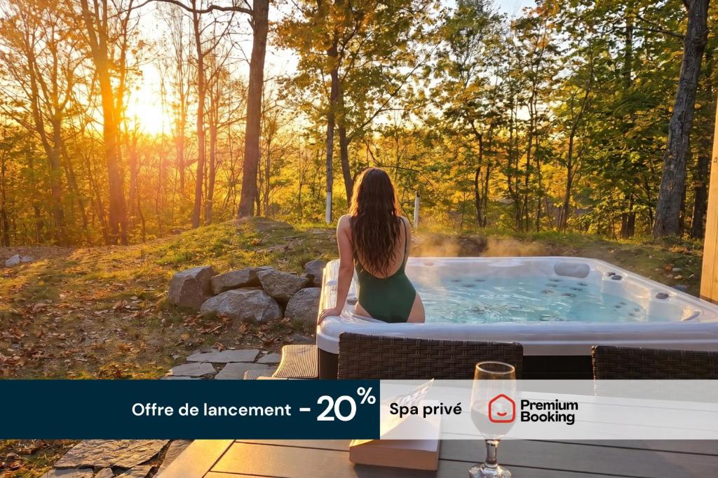 a woman sitting in a hot tub in the woods at Chalet Luméo Private SPA, Golf & carling Lake in Brownsburg