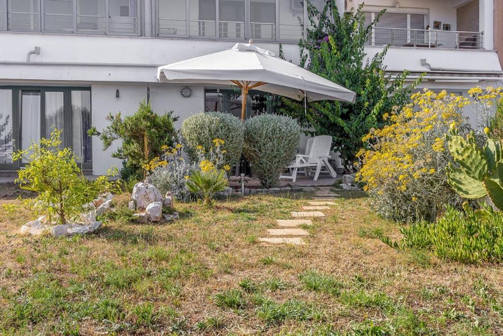 a patio with an umbrella and a chair in a yard at Apartments Villa Ana in Medulin