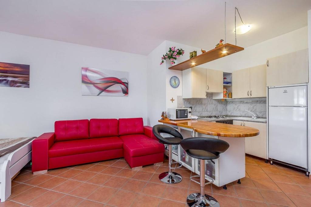 a living room with a red couch and a kitchen at Apartments Villa Ana in Medulin