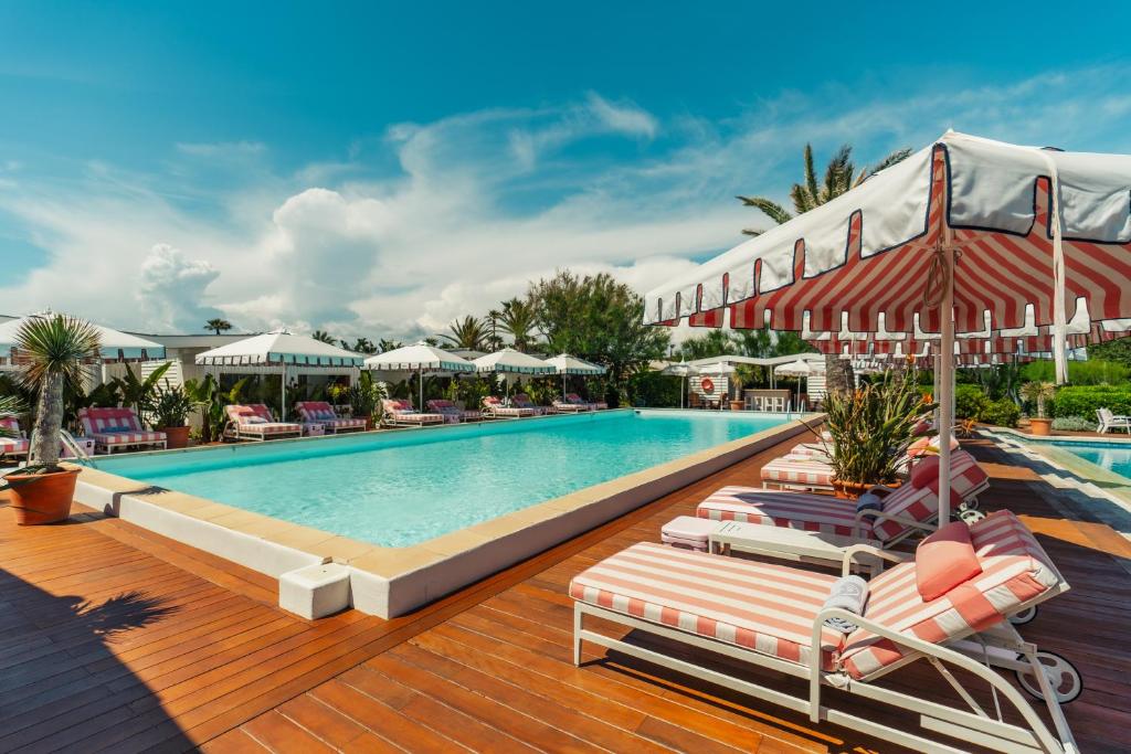 a pool at a resort with lounge chairs and umbrellas at Epi Baie de Pampelonne in Saint-Tropez