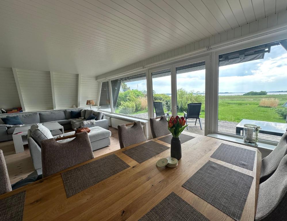 ein Wohnzimmer mit Tisch, Stühlen und Fenstern in der Unterkunft Schleirauschen in Klein Brodersby