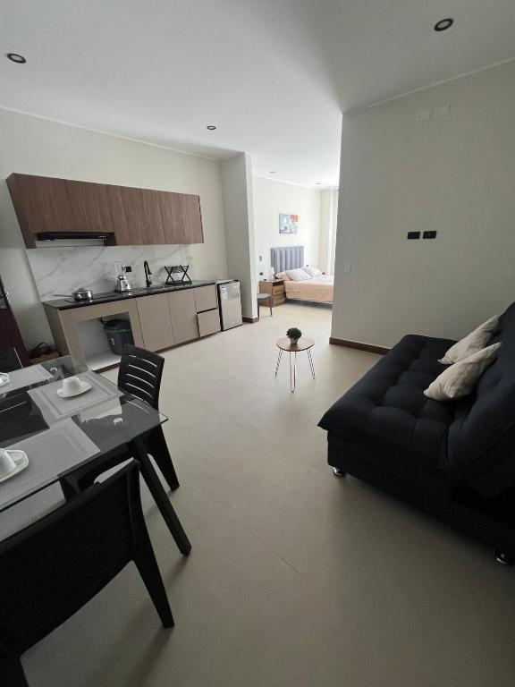 a living room with a black couch and a kitchen at Monoambiente Amplio in Tarija