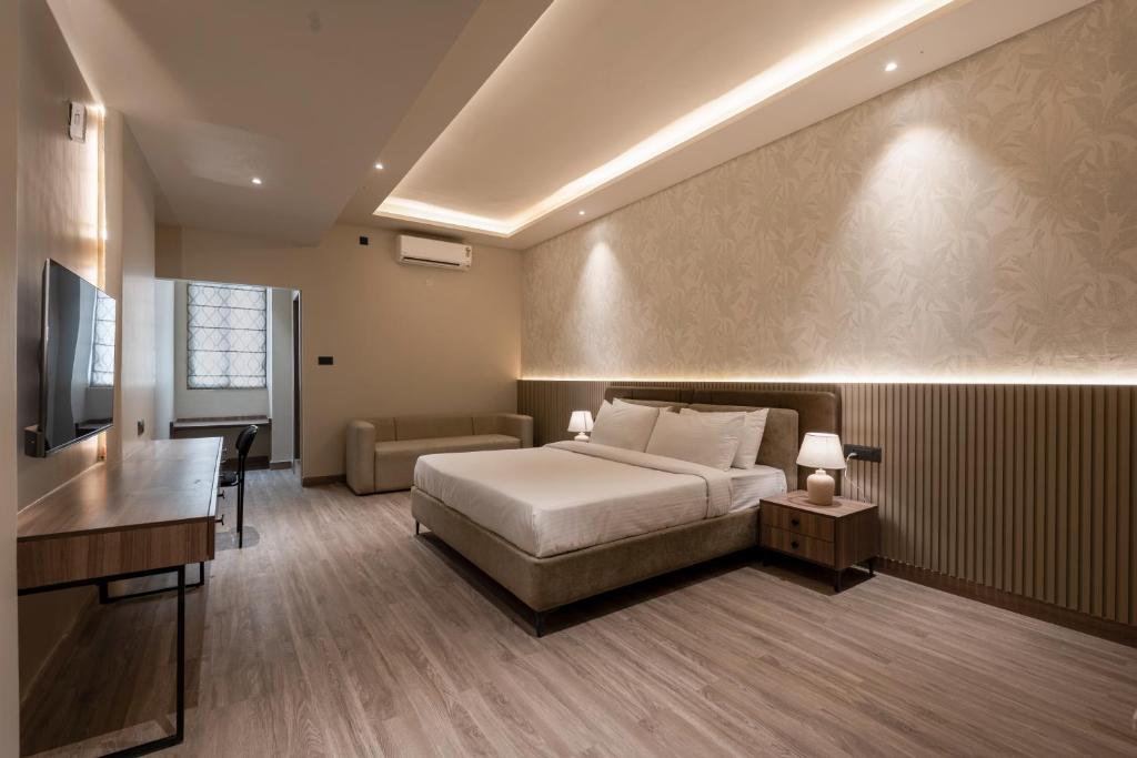 a bedroom with a bed and a desk and a television at Mansions by HomeSlice in Bangalore