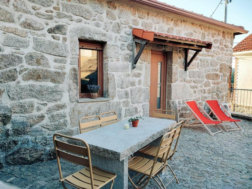 a stone house with a table and chairs on a patio at Casa dos Côtos. in Castro Laboreiro