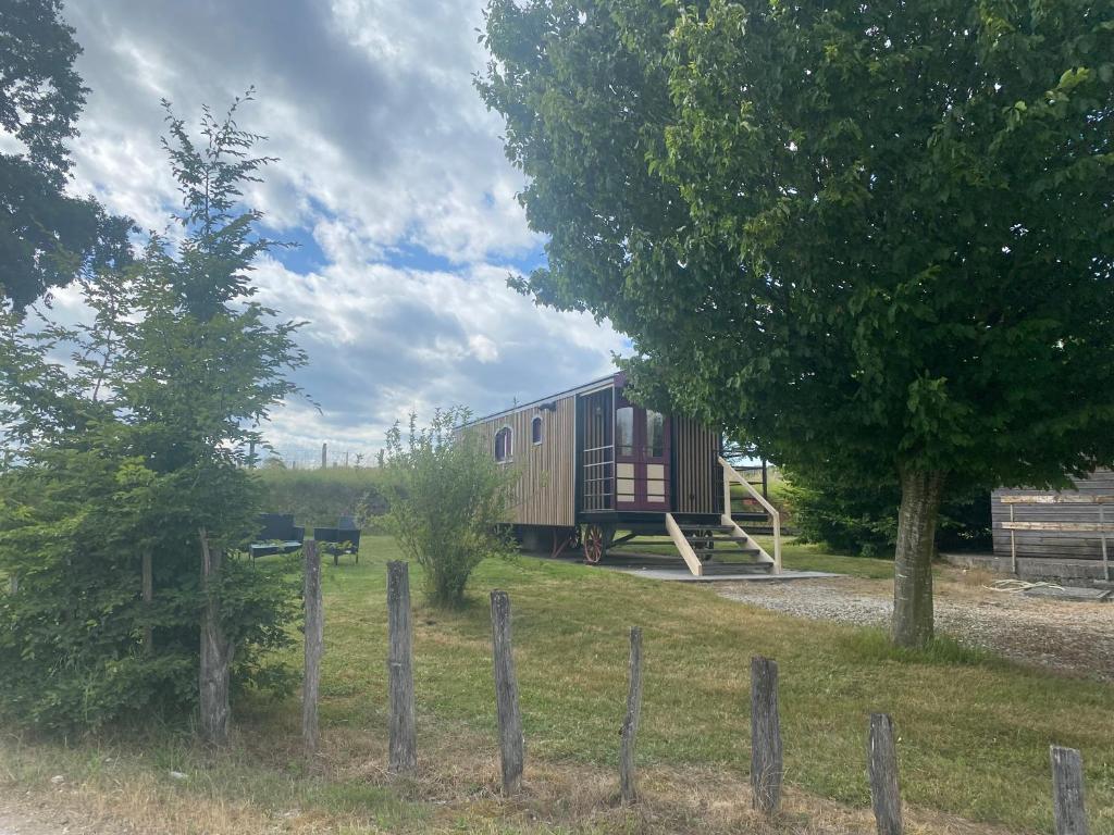 a train car sitting in a field next to a fence at La Roulotte au Paradis in Arc-et-Senans