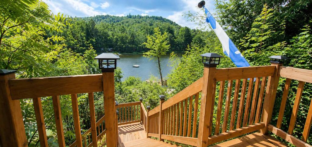 a wooden deck with a view of a lake at Serenity Tree house on the lake in Huberdeau