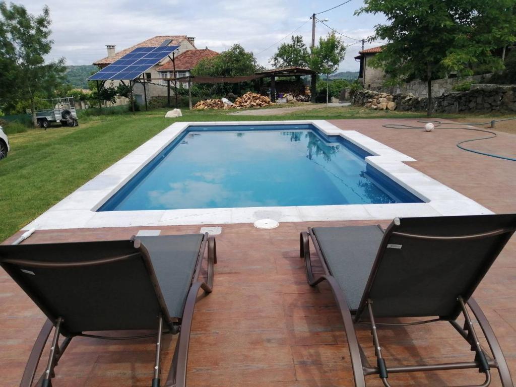 a swimming pool with two chairs and a table at Casiñas De Acevedo in Junquera de Ambía