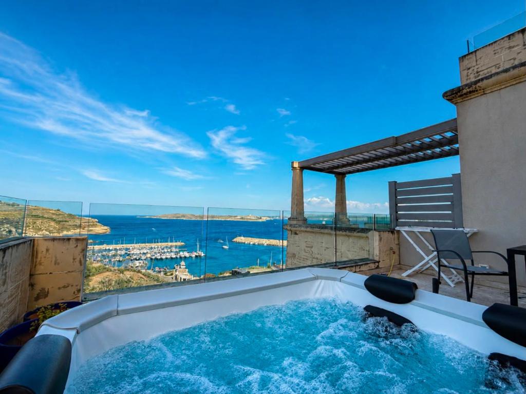 a hot tub on a balcony with a view of the ocean at Vista Laguna - Harbour View - Private Jacuzzi in Għajnsielem
