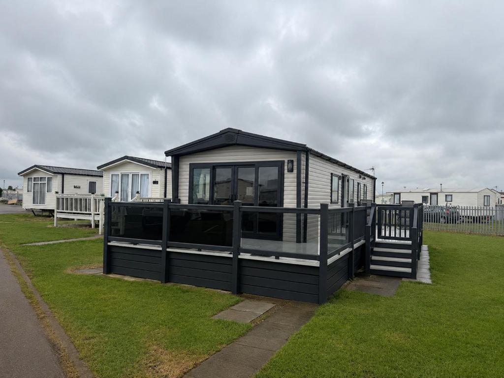 a house with a black roof on a grass field at 3 Bed - Sleeps 8 - Family & Pet Friendly in Skegness