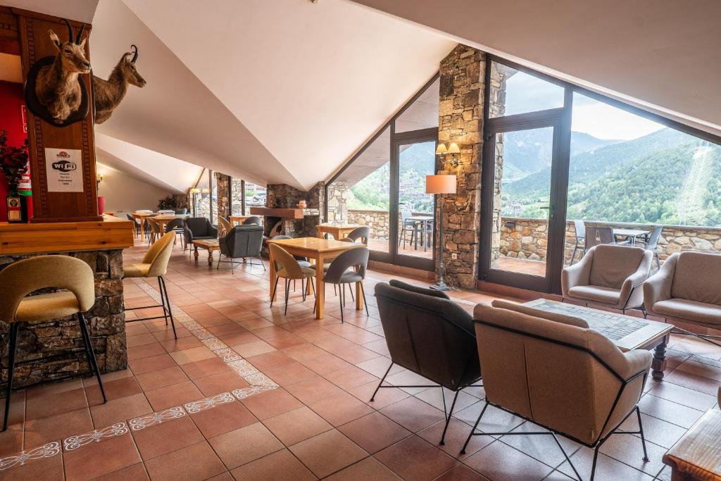 a restaurant with chairs and tables and a large window at Hotel Ransol in El Tarter