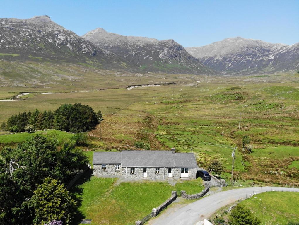 a house in a field with mountains in the background at Twelve Bens Lodge in Recess