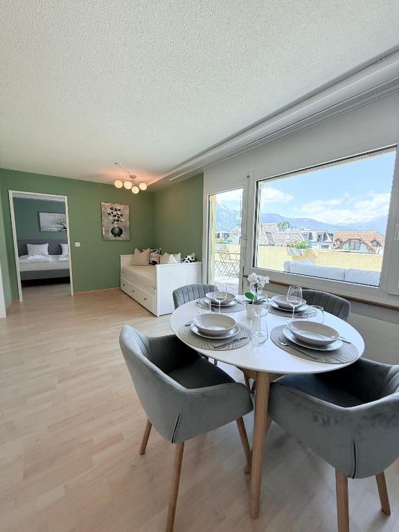 a dining room with a table and chairs and a living room at Cozy Swiss Apartment - City & Mountain view in Interlaken