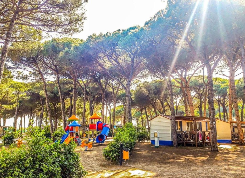 a park with a playground and a small house at Camping Pineta - Nikoli Tour in Cesenatico