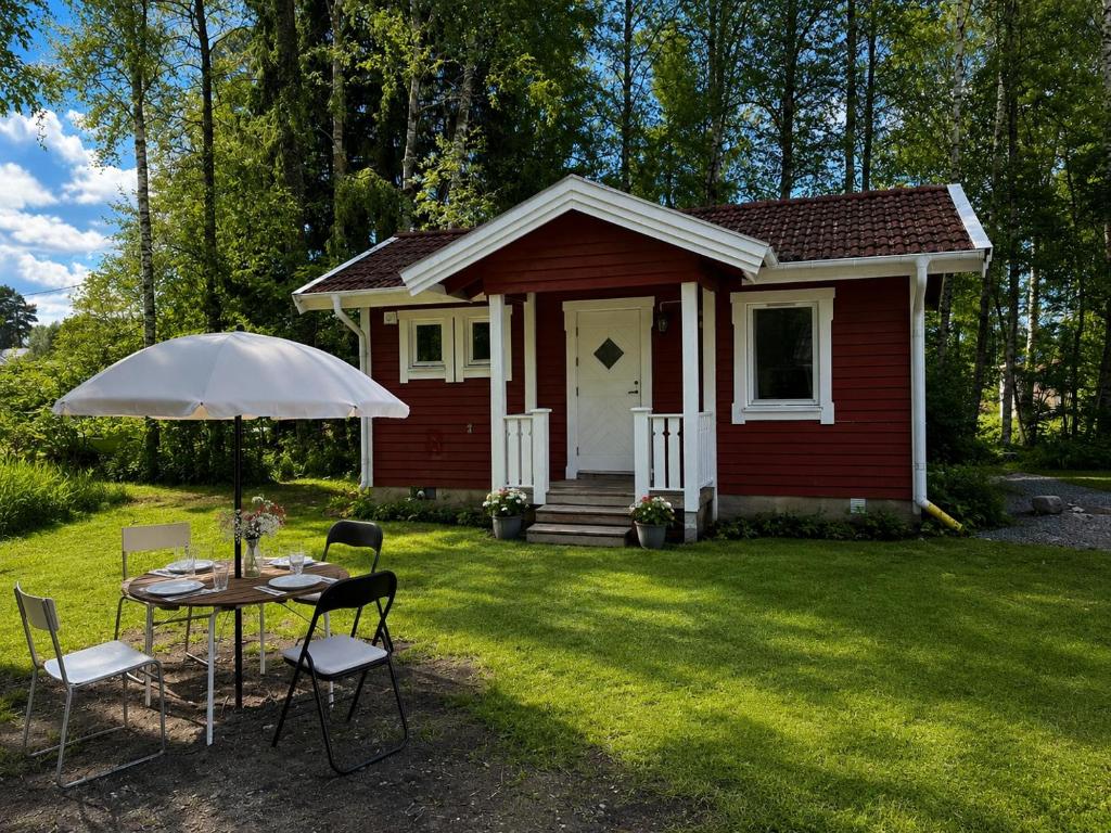 a small red house with a table and chairs at Nyrenoverad stuga mellan två sjöar in Järlåsa