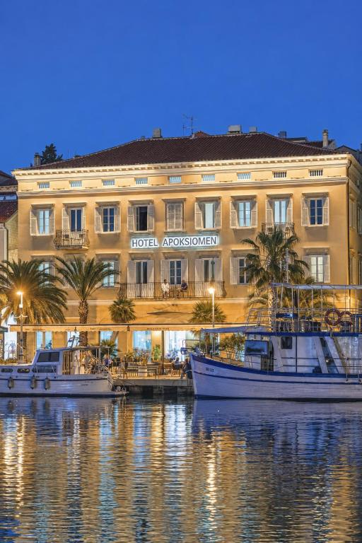 a hotel with boats in the water in front of it at Hotel Apoksiomen in Mali Lošinj