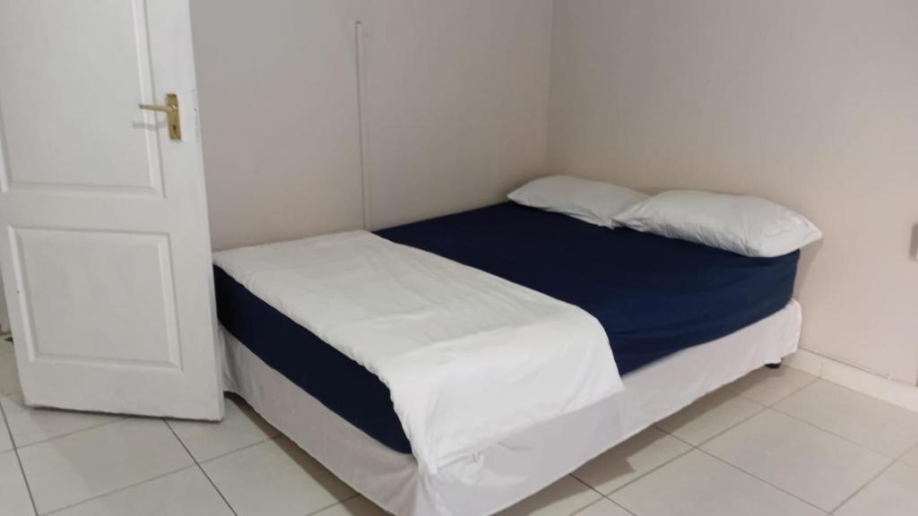 a small bedroom with a bed with blue and white sheets at Jack & Ace in Durban
